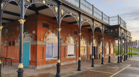 A red building with arches in front. 