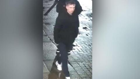 Man wearing white trainers and a black coat