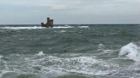 Choppy seas around the Tower of Refuge, a small stone castle-like structure in Douglas Bay.