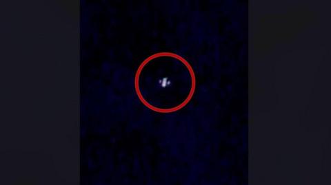 An image of an alleged drone caught on camera in the night sky above New Jersey. A red ring is around it