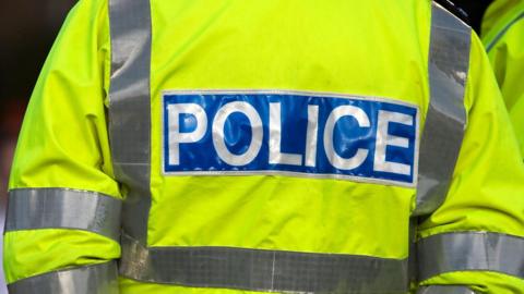 A close up of a police officer wearing a fluorescent yellow police uniform jacket.