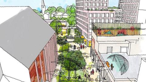 Green area with grass and trees in the centre with walkways either side. There is a tall building to the left with a grey roof and a single-storey roof to the right on which people are standing. There is a multi-storey building beyond to the right and a church in the distance.