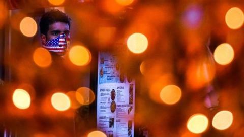 A waiter in Miami wears a mask during the dinner rush