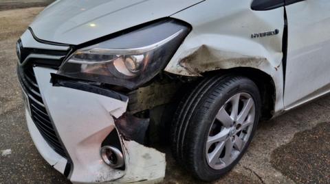 A white car that has damage at the front of it