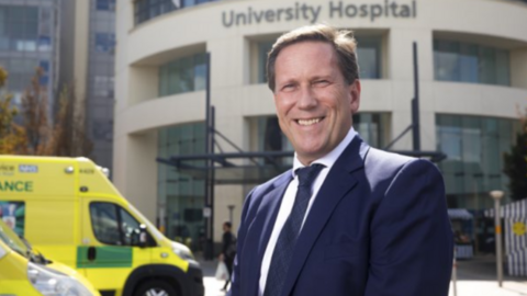 Prof Andy Hardy standing next to an Ambulance in front of a hospital building