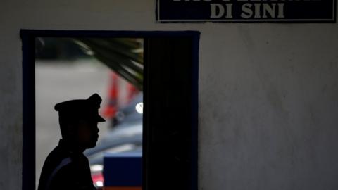 The silhouette of a Malaysia Royal Police officer is seen inside the Sepang District Police headquarters, 17 February