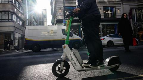 A man rides a rented "Lime" e-scooter on Oxford Street.