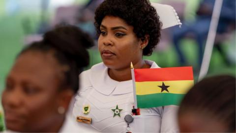 A nurse with a Ghana flag looks on during independence day celebrations at the Jubilee House on 6 March 2025 in Accra.