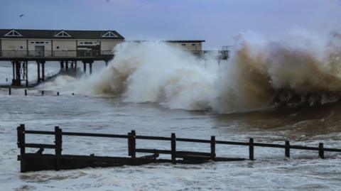 Waves crashing into a pier with seafoam present on top of the water