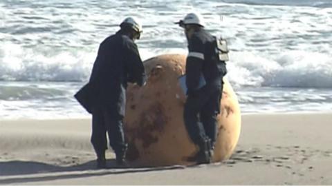 Officials standing next to metal sphere