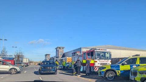 Police cars and fire trucks are parked across a number of disabled parking bays outside the Teesbay Shopping Centre.