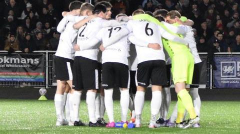 Merthyr Town players in a huddle before a winter game over close rivals Hereford Town in the National League North.