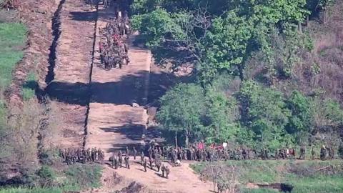 Group of soldiers on an unpaved road, surrounded by vegetation