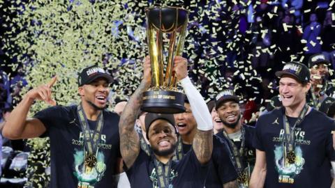 Damian Lillard lifts the NBA Cup while his Milwaukee Bucks team-mates celebrate 