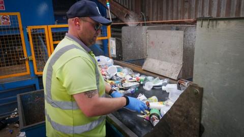 A man sorting recycling on a conveyor belt