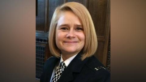 A head and shoulders picture of a police officer in her uniform. She has a blonde bob hairstyle and is smiling directly into the camera.