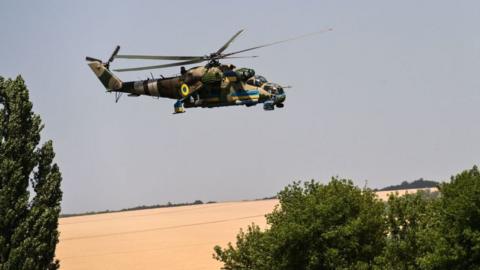 A Ukrainian helicopter flies over a field of wheat