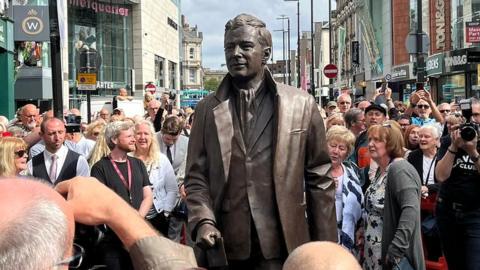 crowds surround Brian Epstein statue