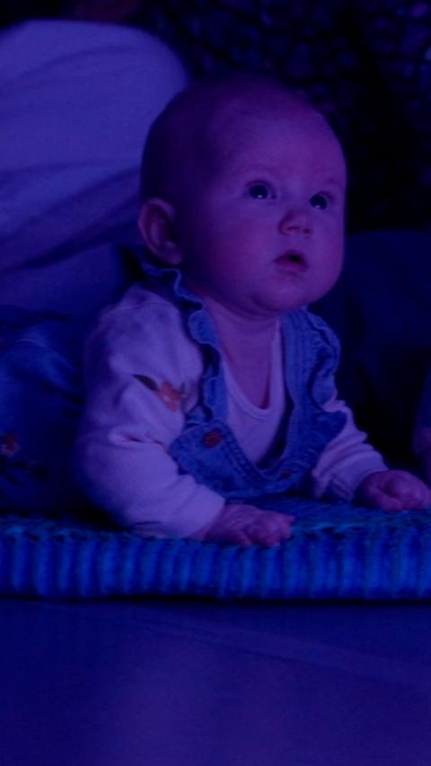 Young baby lying on their tummy, looking at a performance