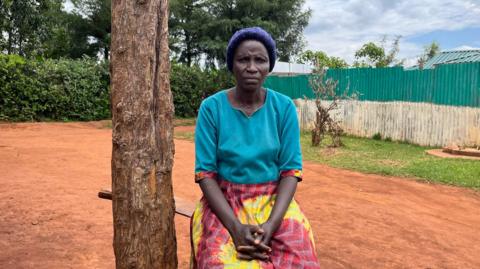 Agnes Barabara sits beside a tree near her home in Kenya