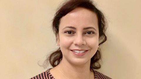 Dr Basheer smiles at the camera. She's wearing a stripy top. Her hair is pulled back into a ponytail and she's wearing pearl earrings.