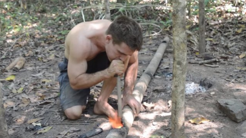 John Plant blowing an ember through a bit of wood