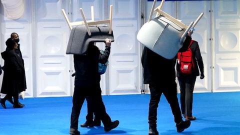 workmen carry COP26 chairs