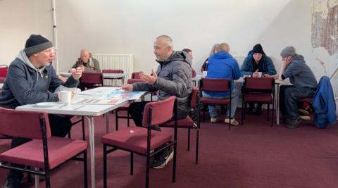 People sat around tables drinking tea and talking