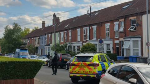 Police officer and police car on street of terraced houses 