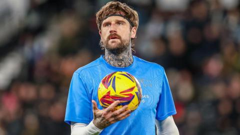 Sonny Bradley with a football in hand while warming up for Derby