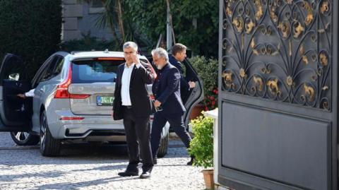 A staff member guards the gate of the Iranian Consulate as a European delegation arrives in a car ahead of nuclear talks, in Istanbul, Turkey, 25 July 2025