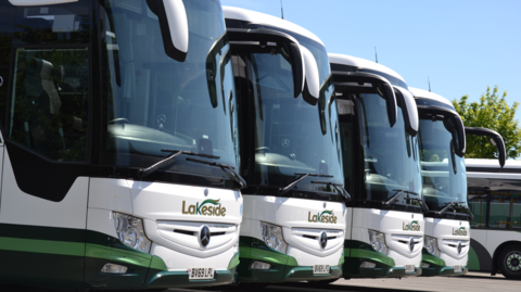 The fronts of four white coaches with dark windscreens in a row