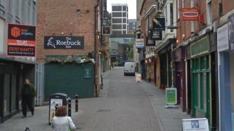 A narrow street with bars either side.