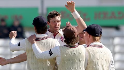 Craig Overton is hugged by Somerset team-mates after taking a wicket