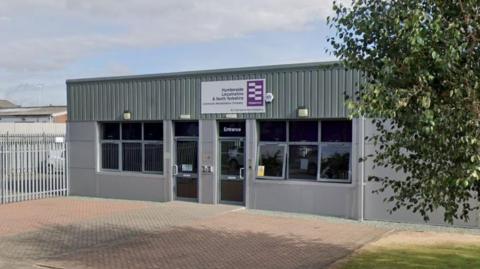 A Google Street View of Humberside, Lincolnshire and North Yorkshire probation office in Grimsby. It shows the outside of a grey office building. There is a tree on the right.