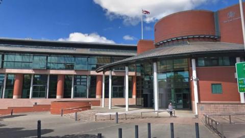 Streetview image of Preston Crown Court, which is a large redbrick and glass building with a round entrance on the right hand side.