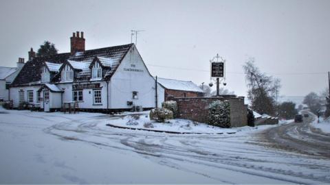 Snow on the road at Hemingby, near Horncastle, with a pub pictured in the background.