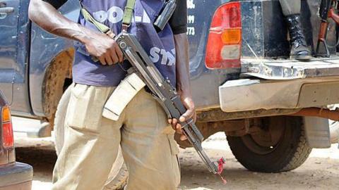 Armed police officer stands beside the back of patrol trucks, holding a rifle in Jos, Plateau State.