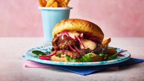 A garlic churrasco chicken burger with a cup of fries on the side.

