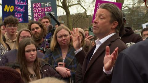 Jamie Oliver speaks to a crowd in a park