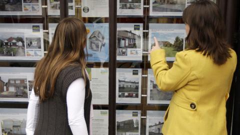 People looking in an estate agents window