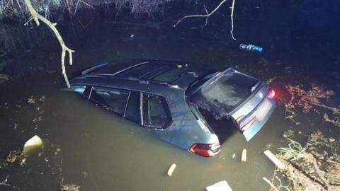 A BMW car gradually sinking in a pond