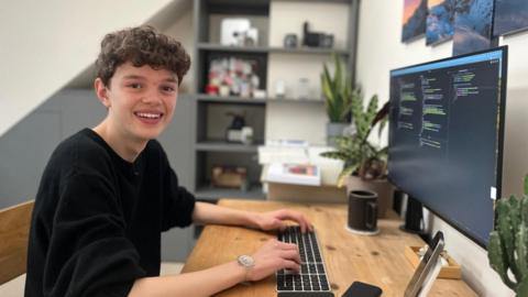 Toby works at his desk in his bedroom