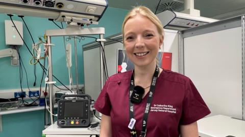 Dr Catherine King, a smiling blonde doctor looks at the camera in the resus room of the hospital.