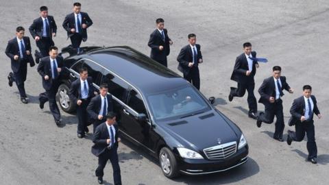 North Korean bodyguards jog next to a car carrying North Korea's leader Kim Jong Un