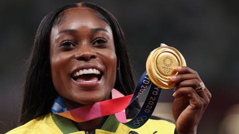 Elaine Thompson-Herah brandishes an Olympic gold medal from Tokyo