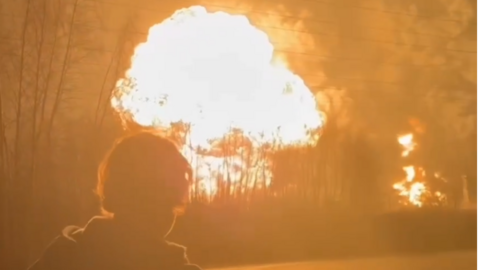 A man stands in the foreground as a fireball erupts at the Ryazan oil refinery