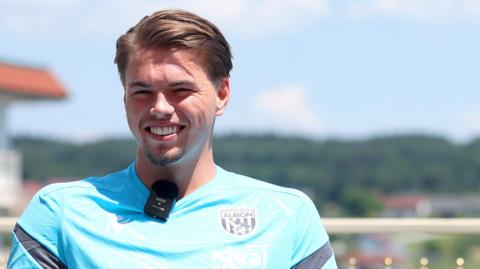 A smiling Josh Griffiths wearing a light blue West Brom training shirt