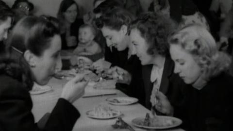 A group of women in the 1940s eat a meal at a long table