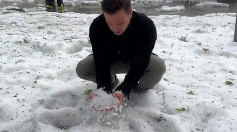 A man picking up hail stones